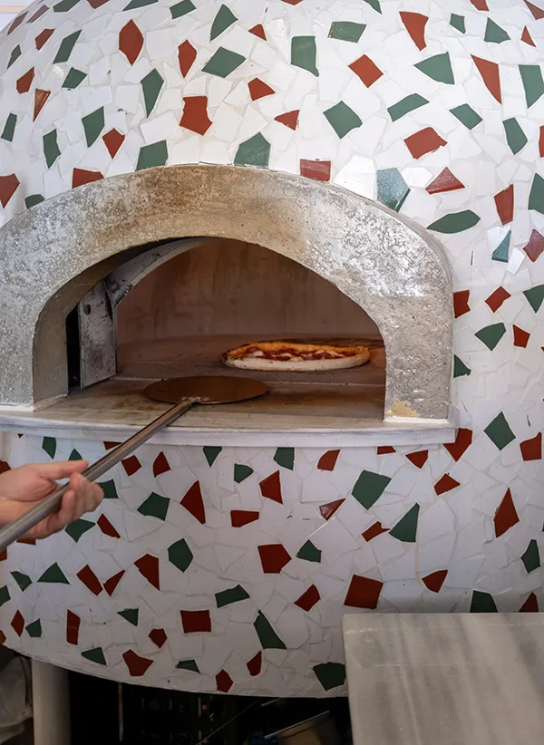 Chef placing cheese on raw pizza bread
